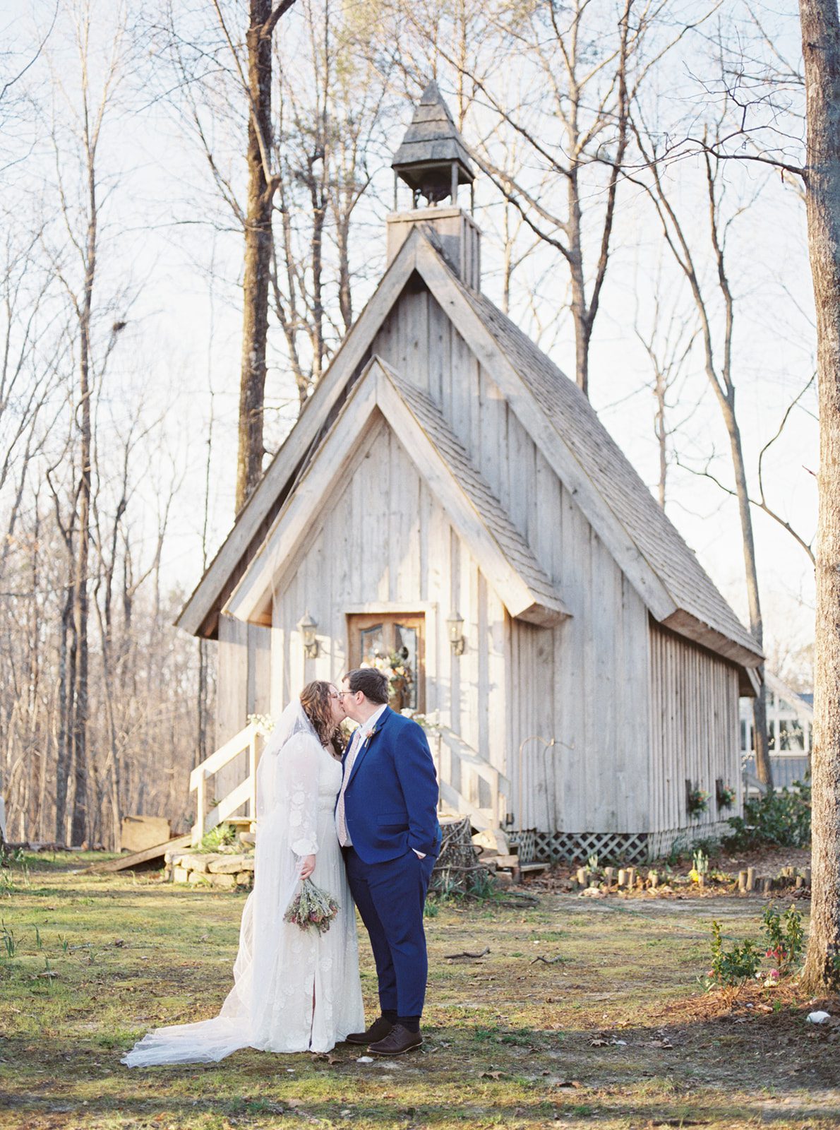 The bride and groom stand in front of the chapel at Fernwood of Mentone in Northeast Alabama during winter