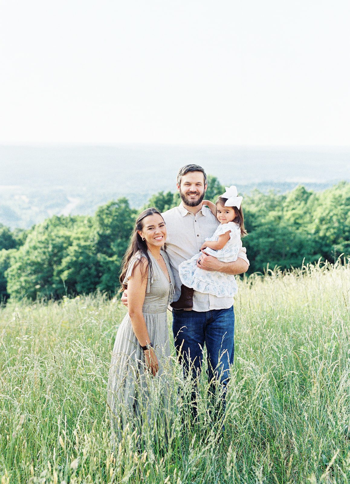 A family stands and smiles in the tall grass at Citadel Rock in Fort Payne, Alabama