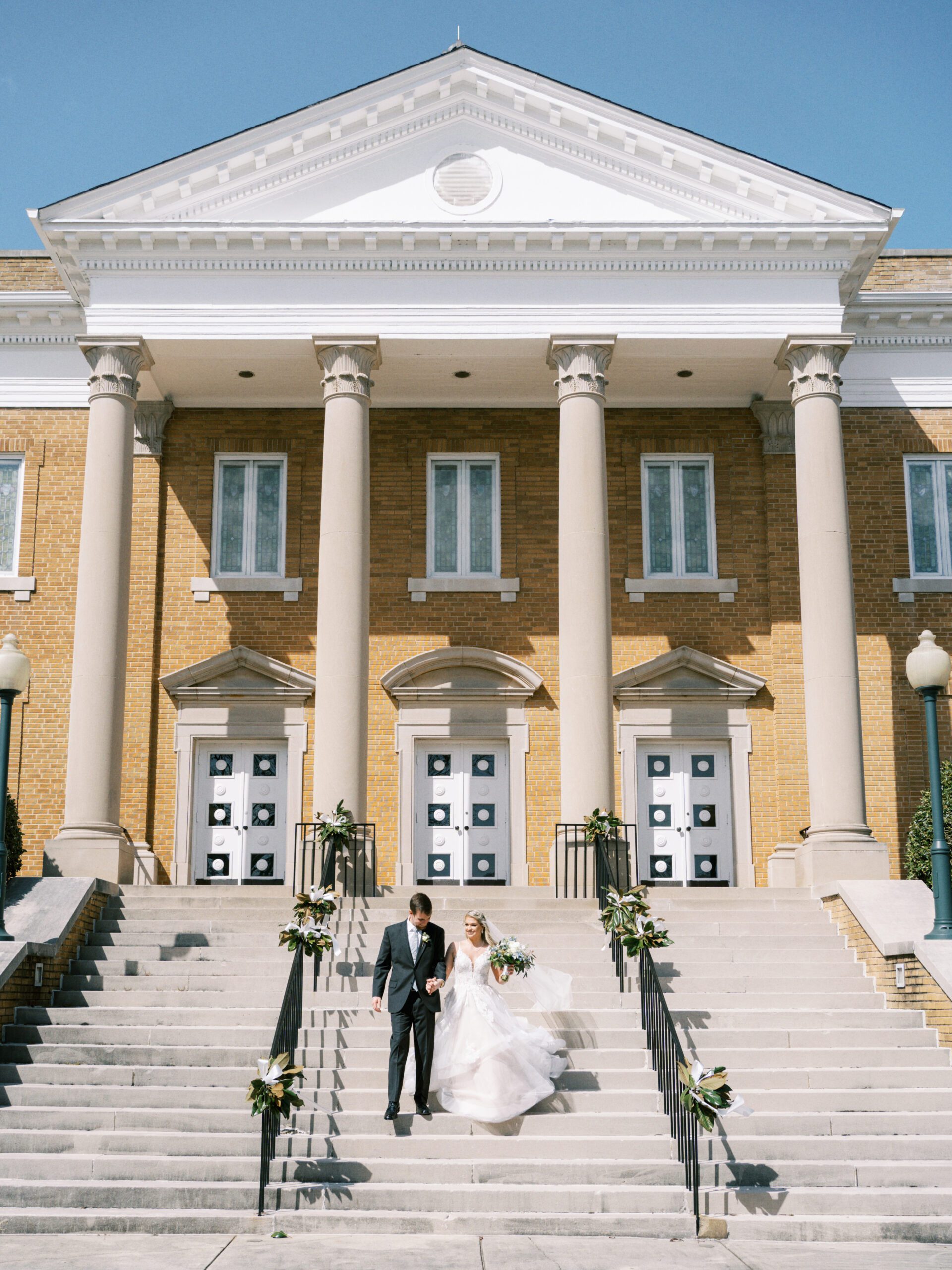 Bride and groom walk down the church steps at First United Methodist Church in Athens, Alabama