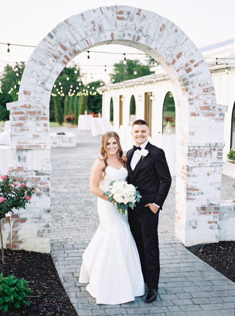 Bride and groom pose under the arch at Blackberry Ridge, a Chattanooga wedding venue, by Kelsey Dawn Photography
