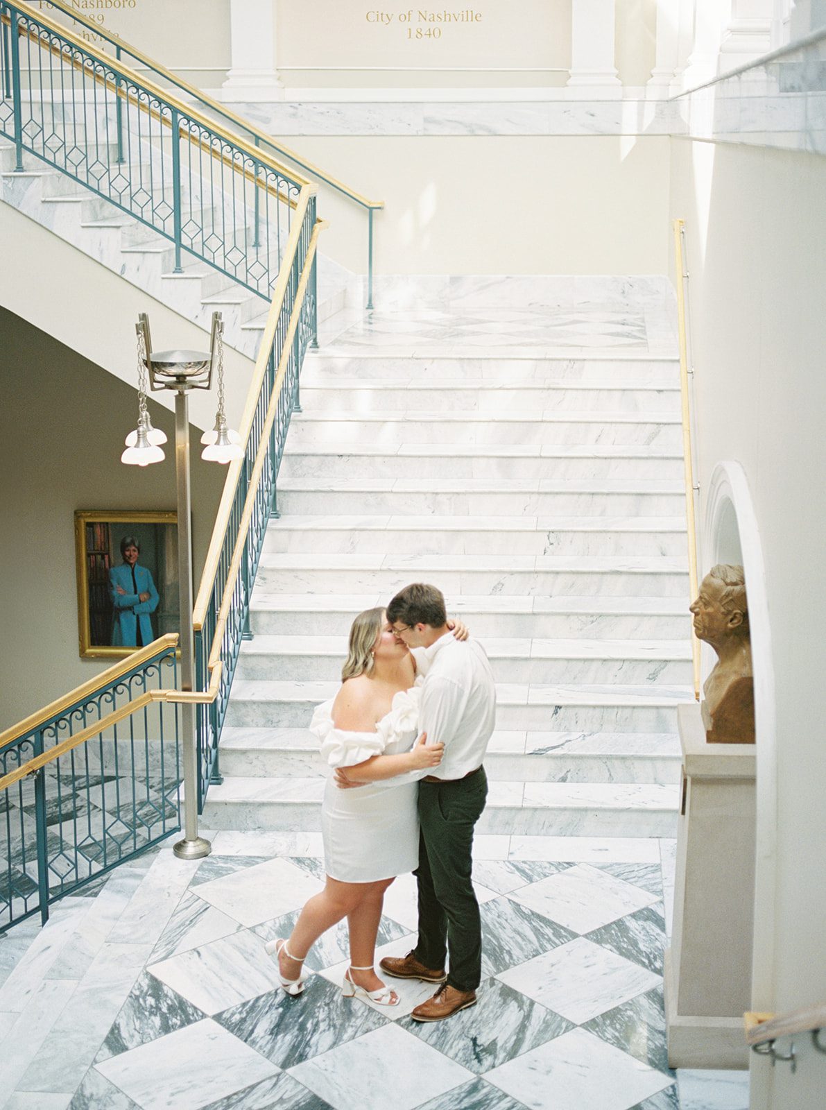 Film picture of engaged couple on checker marble floor in Nashville Public Library with bright background and light coming in